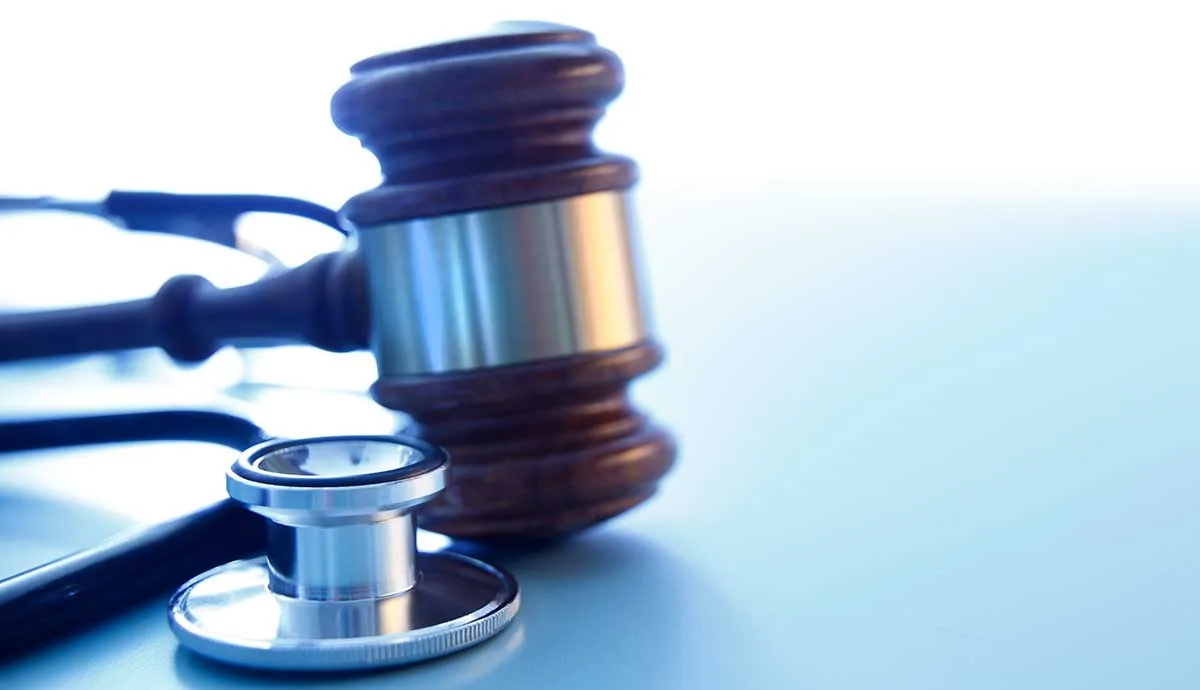 A gavel and a stethoscope on a blue background representing the intersection of the medical and legal industries.